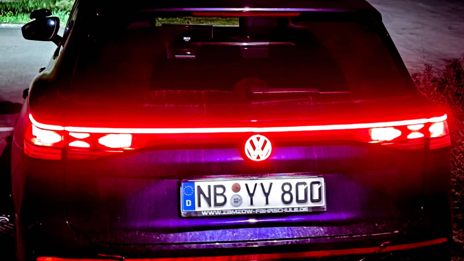 Detailaufnahme der leuchtenden 3D-Heckleuchten und des beleuchteten VW-Logos am Heck unseres VW Tayron.