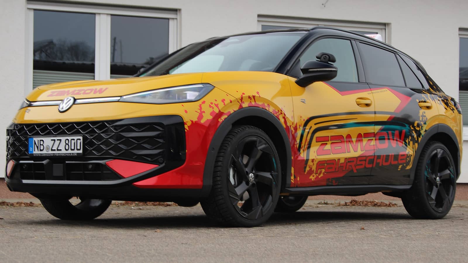Frontansicht des gelben VW T-Roc Fahrschulautos: R-Line Logo, Zamzow-Schriftzug und LED-Scheinwerfer der Fahrschule Zamzow in Neubrandenburg.